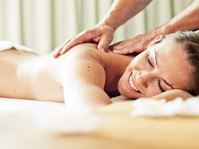 Eine glückliche Frau entspannt bei einer Massage in einem Wellnessbereich von einem Hotel in Bad Füssing.