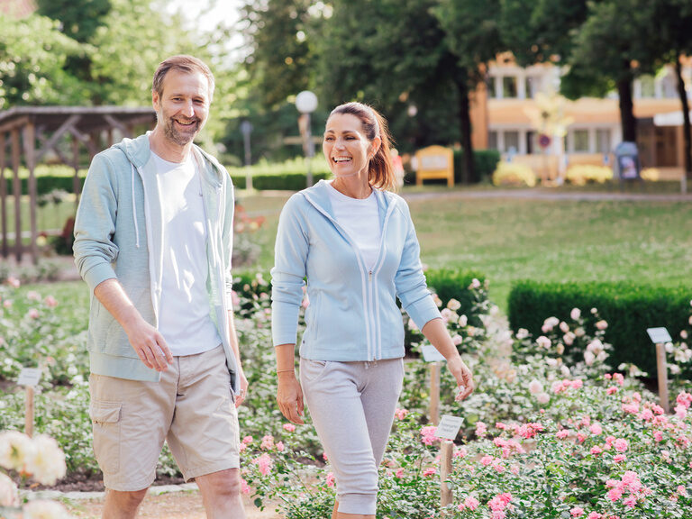 Ein Paar wandert lächelnd durch den blühenden Blumengarten mitten in Bad Füssing.