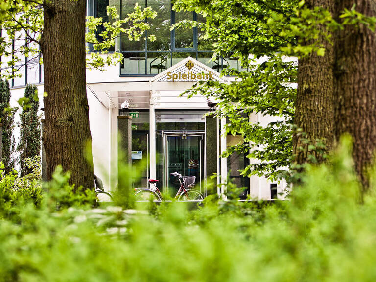 Ein imposantes Spielbankgebäude umgeben von grünen Bäumen inmitten vom Zentrum von Bad Füssing.